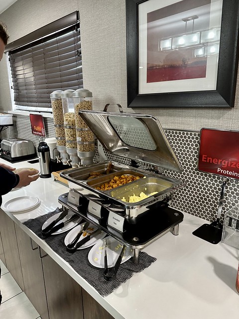 Silver chafing dishes with link sausage, fried potatoes and scrambled eggs in the hotel breakfast kitchen.