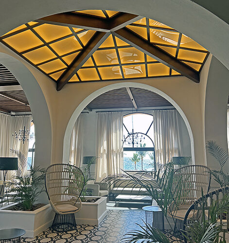 Black and white tile floor with fern trees and vaulted ceiling in a lounge setting at Excellence Riviera Cancun.