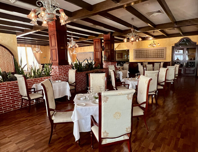 Elegant restaurant with wooden floors and brick wall at Excellence Riviera Cancun.