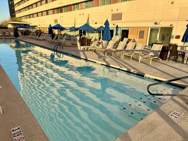 Terrace swimming pool with patio chairs and blue canvas umbrellas on the fourth floor of the Sheraton hotel. 