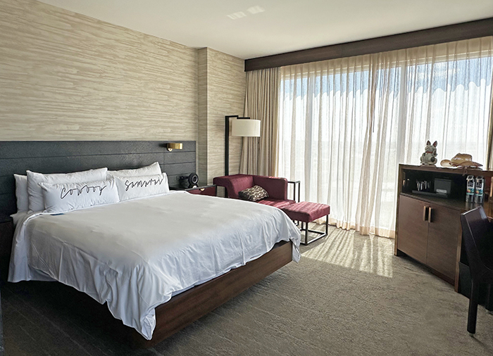 King bedroom at Renaissance Dallas Plano features white linens, red accents and wall of windows