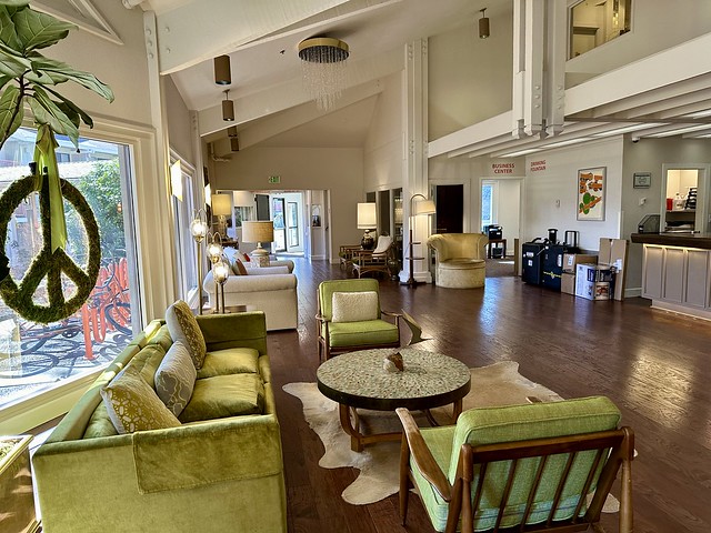 Mid-century modern lime green velvet sofa with 2 matching chairs flank the hotel lobby reception area. A giant green-mossy peace sign is suspended from above the picture window looking out to the front of the Ashland, Oregon hotel. 