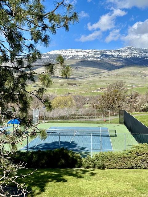 Tennis court at Ashland Hills Hotel with snow-dusted hills in the distance. 