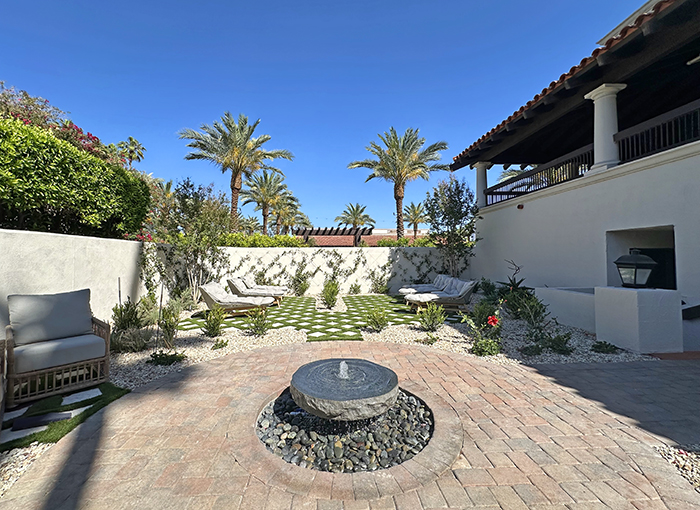 Walled-in spa zen garden with bubbling stone fountain, plush loungers and a crosshatch lawn of grass and stone pavers