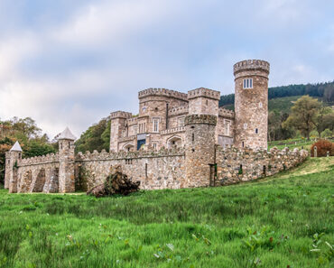 Castle with stone turrets with verdant mountains in background