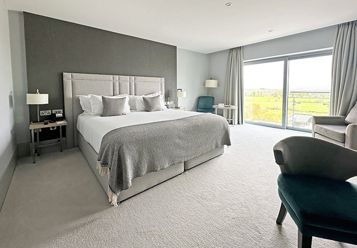 Guestroom in shades of gray and white with large windows overlooking farmland