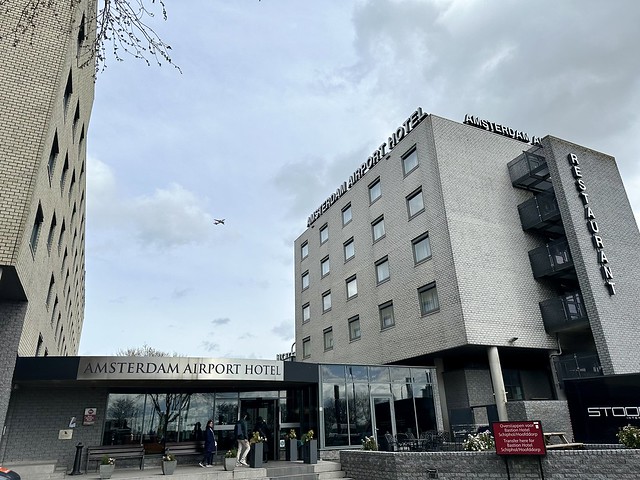 Two towers join Best Western Plus Amsterdam Airport hotel. An airplane can be spotted flying between the 2 buildings. 