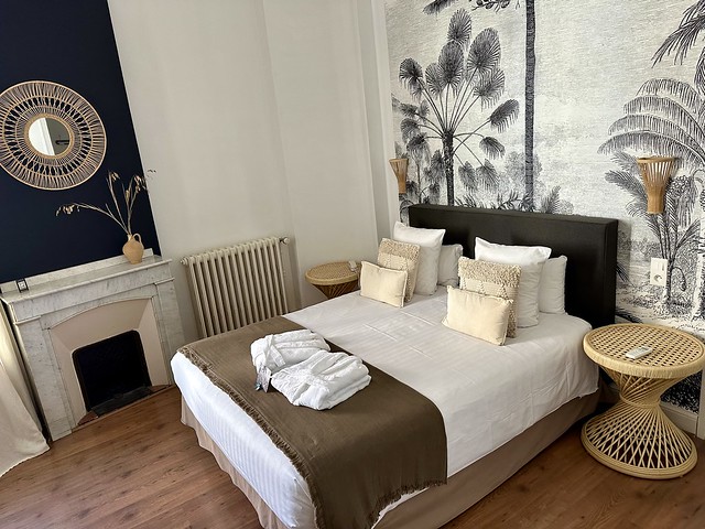 Room 17 with king bed, six white pillows, 2 white cotton robes. A hand-stenciled black and white mural is behind the bed. 