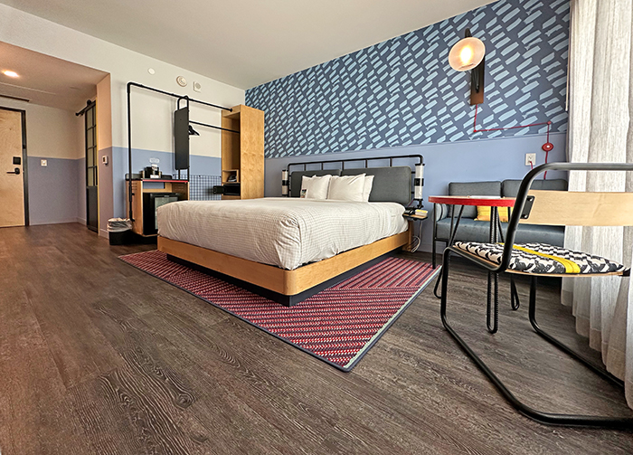 A typical guestroom at Caption by Hyatt features minimalist furnishings, playful wallpaper and soothing blue tones.