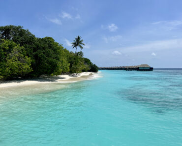 Aqua seawater against white sand beach and overwater bungalows.