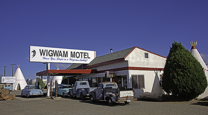 Vintage trucks sit in front of a former gas station that serves as the lobby for the Wigwam Villages