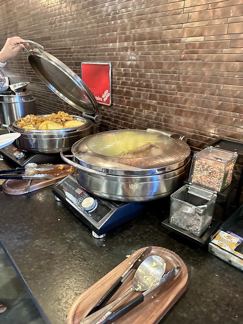 Breakfast buffet with chafing dish open to cheese omelet. A hot dish, with closed lid, held scrambled eggs and pork sausage. 