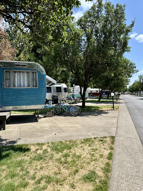 Blue vintage trailer and 2 blue cruiser bikes are parked along the lane at The Vintages Trail Resort. 