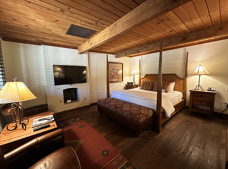 A guest casita with wood floors and ceiling, a four-poster bed and fireplace