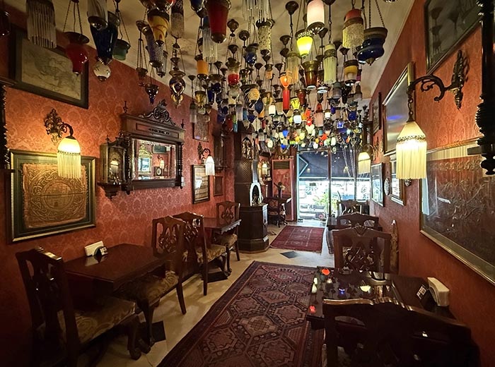 Narrow dining room looks out to street. Ceiling is covered in dozens of hanging glass lamps.