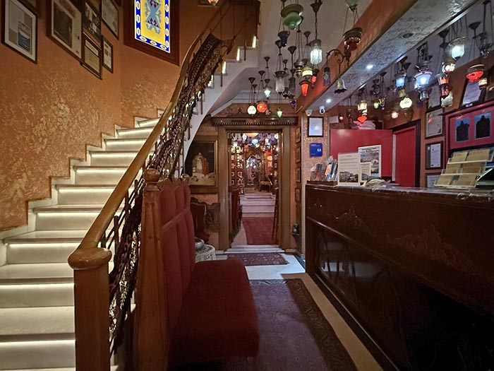 Narrow hotel lobby with check in desk and curved marble staircase